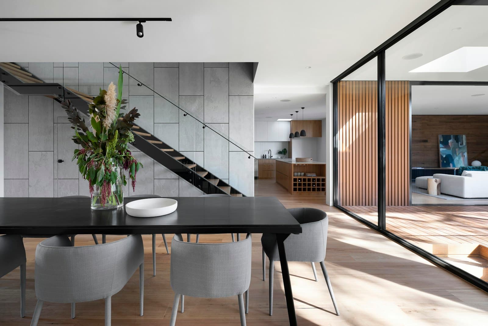 Dark dining table beside a sculptural staircase